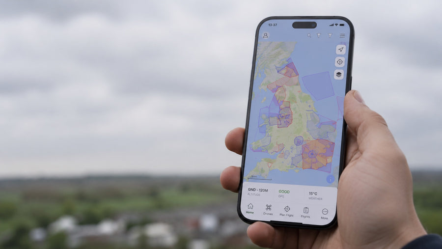 A hand holding a phone showing a UK airspace map in a flight planning app