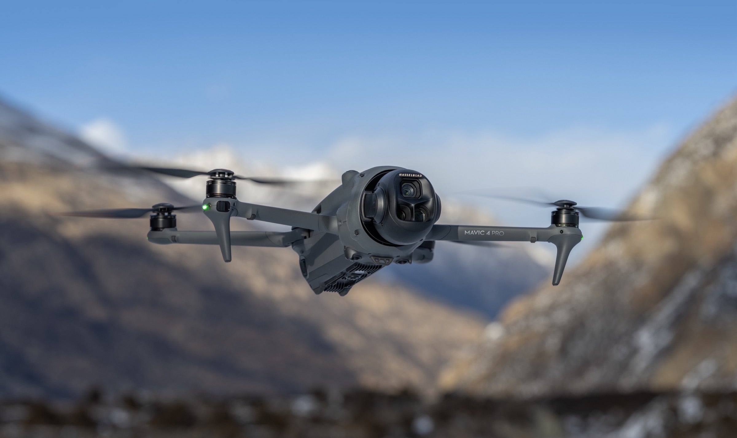 DJI Mavic 4 Pro hovering in front of snow covered mountains