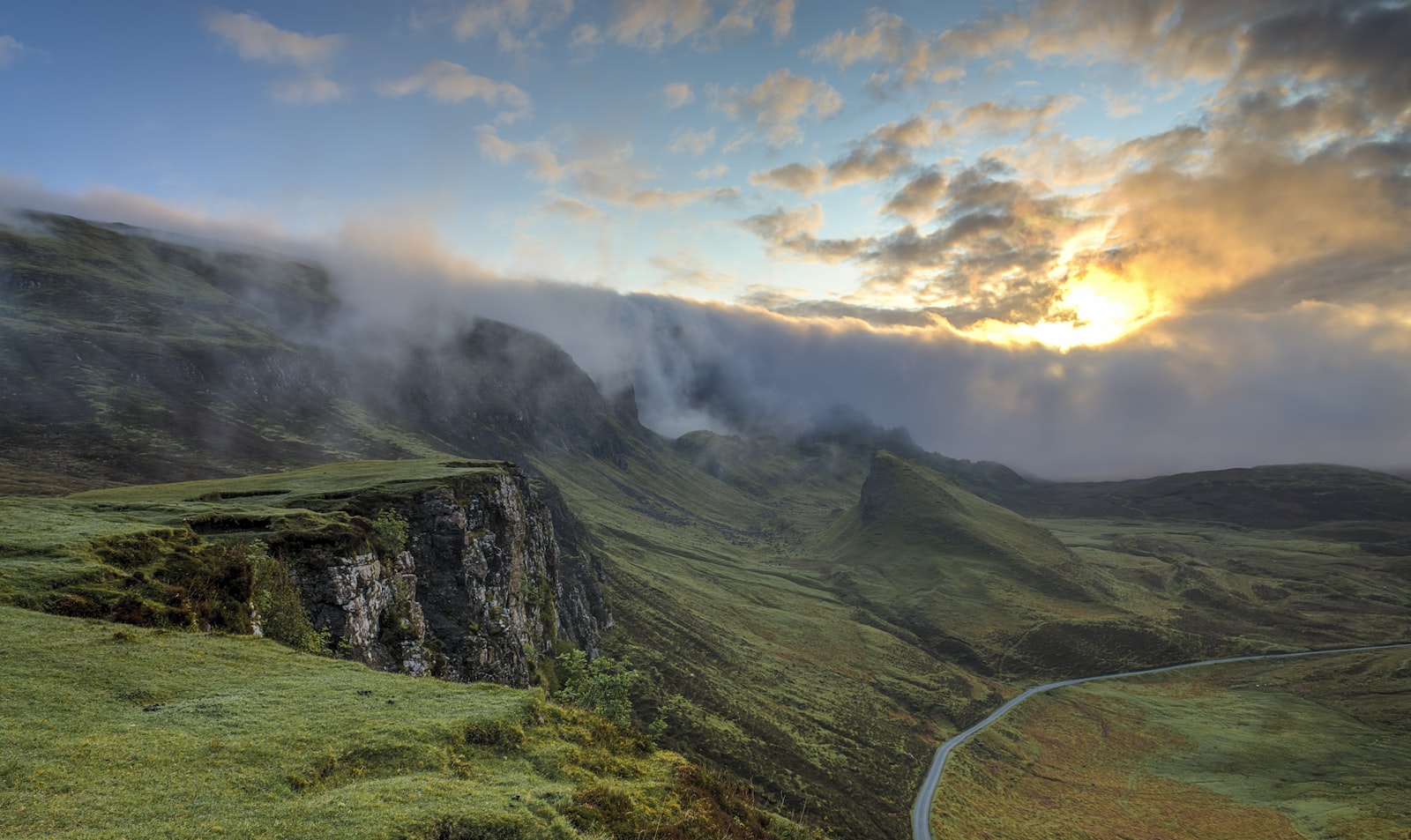 Sunrise over a Scottish ridge line, low cloud spilling across the hills